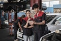 Two Asian professional automotive mechanics working at a service garage. Royalty Free Stock Photo