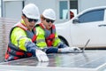 Two Asian professional technician workers sit near solar cell panel and use laptop to discuss about work in concept of green Royalty Free Stock Photo