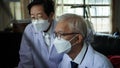 Two Asian senior doctor health care technician looking at patient information and discussing computer screens Royalty Free Stock Photo