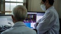 Two Asian senior doctor health care technician looking at patient information and discussing computer screens Royalty Free Stock Photo