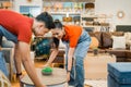 two Asian shop assistants in aprons move a table together while working