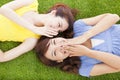 Two asian sisters whispering gossip on the grass Royalty Free Stock Photo