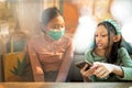 Two Asian teen girls hangout together with only one of them wearing face mask