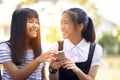 Two asian teenager laughing with happiness face reading message in smart phone screen