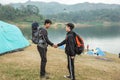 Two asian travelers with shake hand standing near lake