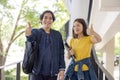 Two Asian university students walking and conversing to class in a magnificent campus building`s walkway Royalty Free Stock Photo