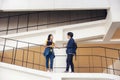 Two Asian university students walking and conversing to class in a magnificent campus building`s walkway Royalty Free Stock Photo