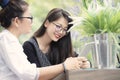 Two asian woman with smart phone in hand talking in home living room with happiness face