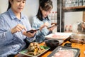 Two asian woman using smartphone to take photo of papaya salad som tam in a restaurant, mother and teenage daughter taking Thai Royalty Free Stock Photo