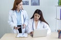 Two asian women doctors discuss meeting doctor`s office medical clinic using laptop consulting patient disease. Asian medical lab Royalty Free Stock Photo