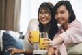 Two Asian women drink orange juice in living room Royalty Free Stock Photo