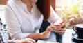 Two Asian women drinking coffee in a cafe and shopping online on smart phones Royalty Free Stock Photo