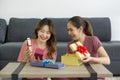 Two Asian women enjoy opening a gift box received for a special occasion