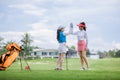 two asian women golfers congratulate high-five and happy smiling at golf course, with the golf bag next to them Royalty Free Stock Photo