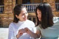 Two asian women holding a crytocurrency in their hands. One of the Asian women gives the coin to the other Asian woman. The