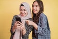 two asian women laughing using a cell phone while looking at the phone screen Royalty Free Stock Photo