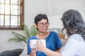 Two Asian women are sitting drinking coffee and chatting in the living room. Royalty Free Stock Photo