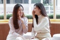 Two Asian women young friends in sweater laughing together put hand cover mouth after they talking to something fun Royalty Free Stock Photo