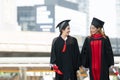 Two Asian young beautiful graduate female students with master and bachelor degree smiling and holding diploma in hand Royalty Free Stock Photo