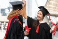 Two Asian young beautiful graduate female students with master and bachelor degree smiling and holding diploma in hand Royalty Free Stock Photo