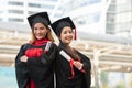 Two Asian young beautiful graduate female students with master and bachelor degree standing smiling and holding diploma in hand Royalty Free Stock Photo