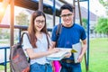 Two Asian young college people discussing about reading book and using laptop for search and learn knowledge. Education and