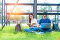 Two Asian young college people discussing about reading book and using laptop for search and learn knowledge. Education and