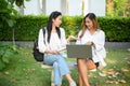 Two Asian young female college students sitting in the park, discussing their project Royalty Free Stock Photo