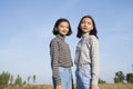 Two Asian young girl standing at the field grass with blue sky Royalty Free Stock Photo