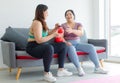 Two Asian young overweight oversized fat chubby plump female sportswomen in casual sportswear sitting on cozy sofa wearing boxing Royalty Free Stock Photo