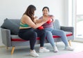 Two Asian young overweight oversized fat chubby plump female sportswomen in casual sportswear sitting on cozy sofa wearing boxing Royalty Free Stock Photo