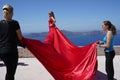 Two assistants are holding the model\'s train of a red dress.