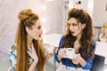 Two astonished surprised attractive women talking in beauty salon. Drinking coffee, preparing to party, having fun Royalty Free Stock Photo