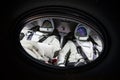 Two astronauts in porthole in space.