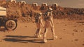 Two astronauts walk toward scientific base on Mars