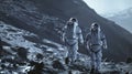 Two astronauts walk on a rocky surface in space. The scene is dark and gloomy