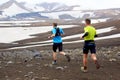 Two athlete runners run a mountain marathon in the snowy terrain of Landmannalaugar. Iceland