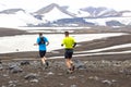 Two athlete runners run a mountain marathon in the snowy terrain of Landmannalaugar. Iceland