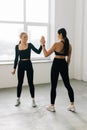 Two athletic beautiful women friend give high five in the gym