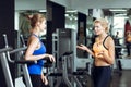 Two athletic blond women talking in gym. Girl communicates with trainer Royalty Free Stock Photo