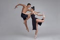 Two athletic modern ballet dancers are posing against a gray studio background.