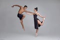 Two athletic modern ballet dancers are posing against a gray studio background. Royalty Free Stock Photo