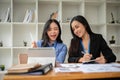 Two attractive Asian female accountants are working on financial reports at a table