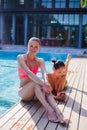 Two attractive blonde and brunette girls with long hair are lying on flor near pool. They wear bikini and swimsuit. They Royalty Free Stock Photo