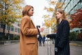 Two attractive casual girls talking standing with suitcase on street