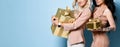 Two attractive girls holding gold gift boxes Royalty Free Stock Photo