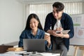 Two attractive and happy Asian businesspeople are checking new project details on a laptop together Royalty Free Stock Photo