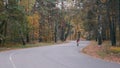 Two attractive male triathletes are training on road bike in autumn park. Young cyclists in sportswear and helmets riding on bicyc