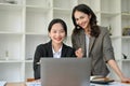 Two attractive Asian businesswomen are working together, looking at laptop screen Royalty Free Stock Photo