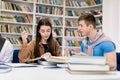 Two attractive smiling confident students, Caucasian girl and boy, sitting at the table while preparing together for Royalty Free Stock Photo